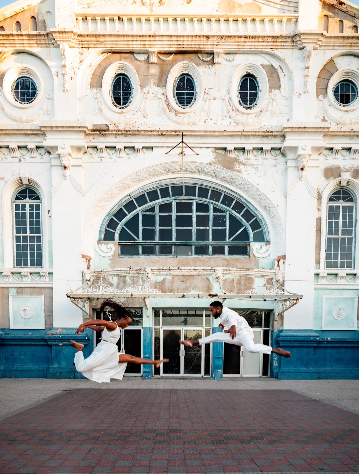 Two dancers leaping toward each other in mid-air in front of the Ward Theatre, in colour